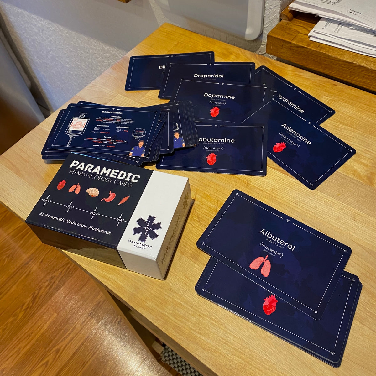 Paramedic Flash pharmacology cards spread out on a table next to the box